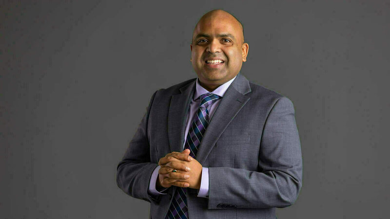Sriram Somanchi smiling with hands knotted in front of his chest.
