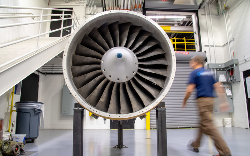 A man walks by a turbomachine in a laboratory.
