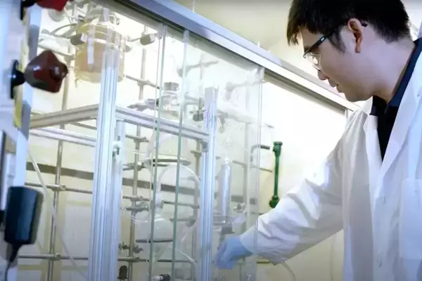 A man stands in his lab in a white lab coat.