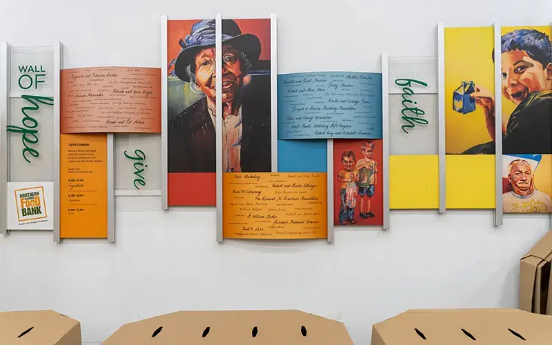 The Wall of Hope at the Northern Illinois foodbank. The words faith, give, and hope are featured, along with photos of people and other text.