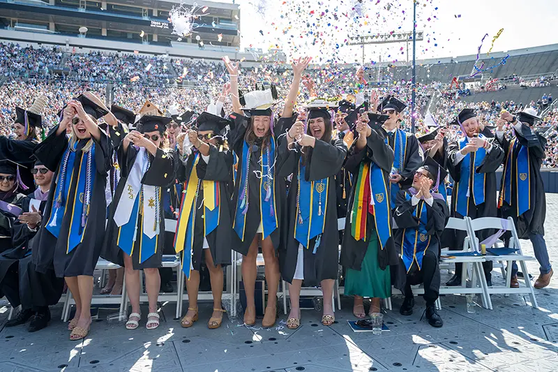 New graduates celebrate by throwing confetti and caps at the completion of the commencement ceremony.