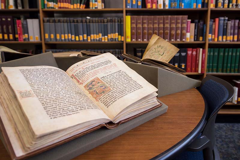 Medieval manuscripts sit open on a table in the library.